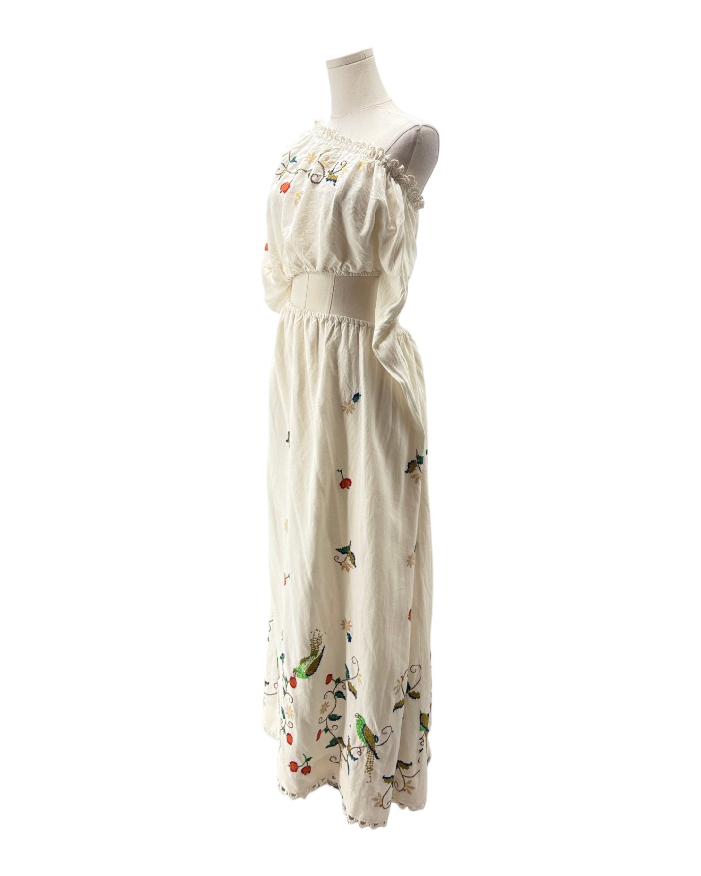 White dress with floral and bird patterns on a mannequin against a white background