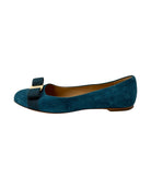Blue suede flat shoe with a bow on a white background