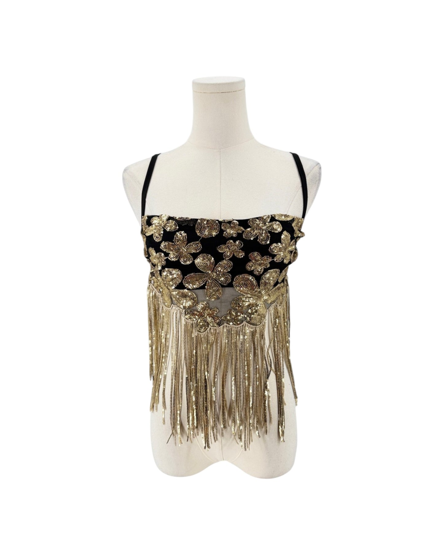 A black and gold embellished sleeveless top with floral sequin details and long fringe, displayed on a white mannequin torso against a white background.