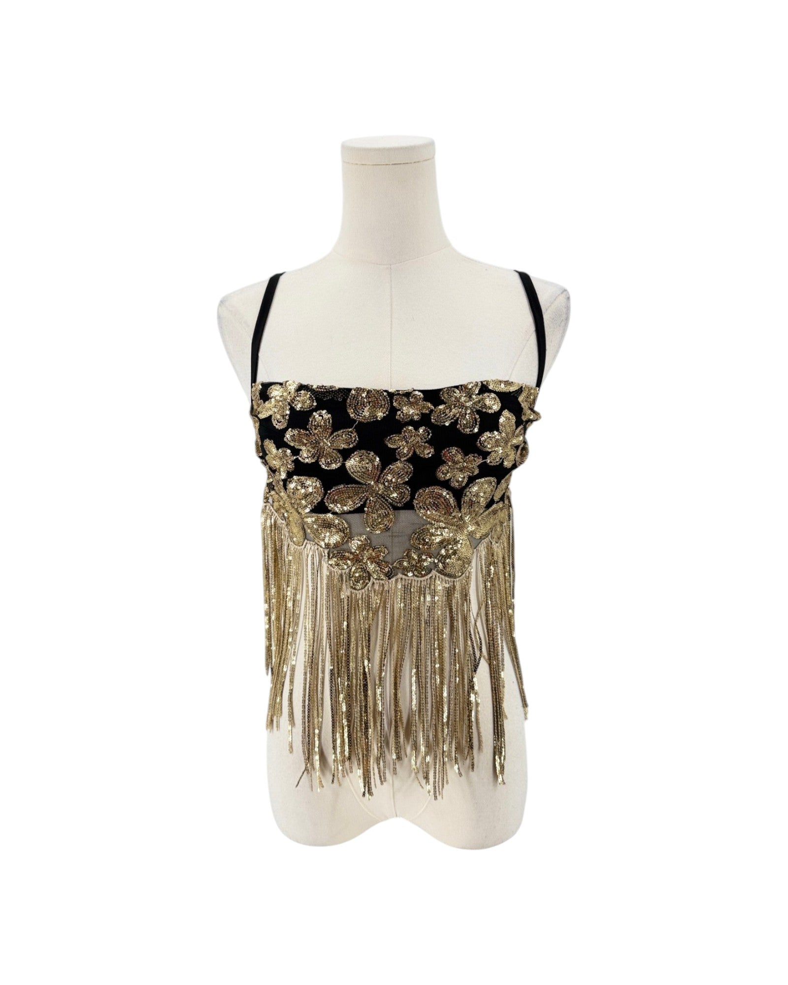 A black and gold embellished sleeveless top with floral sequin details and long fringe, displayed on a white mannequin torso against a white background.