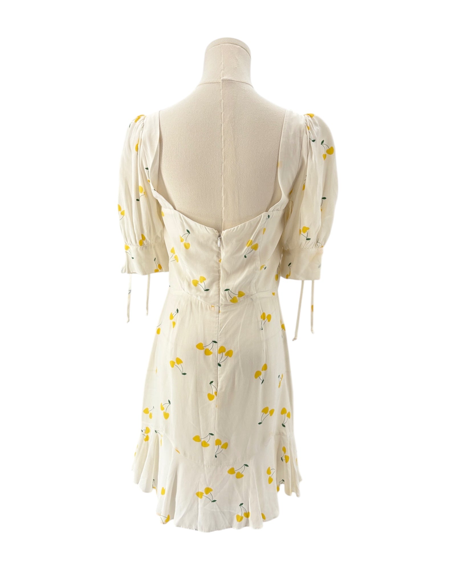 For love and lemons white dress with yellow floral pattern on a mannequin against a white background