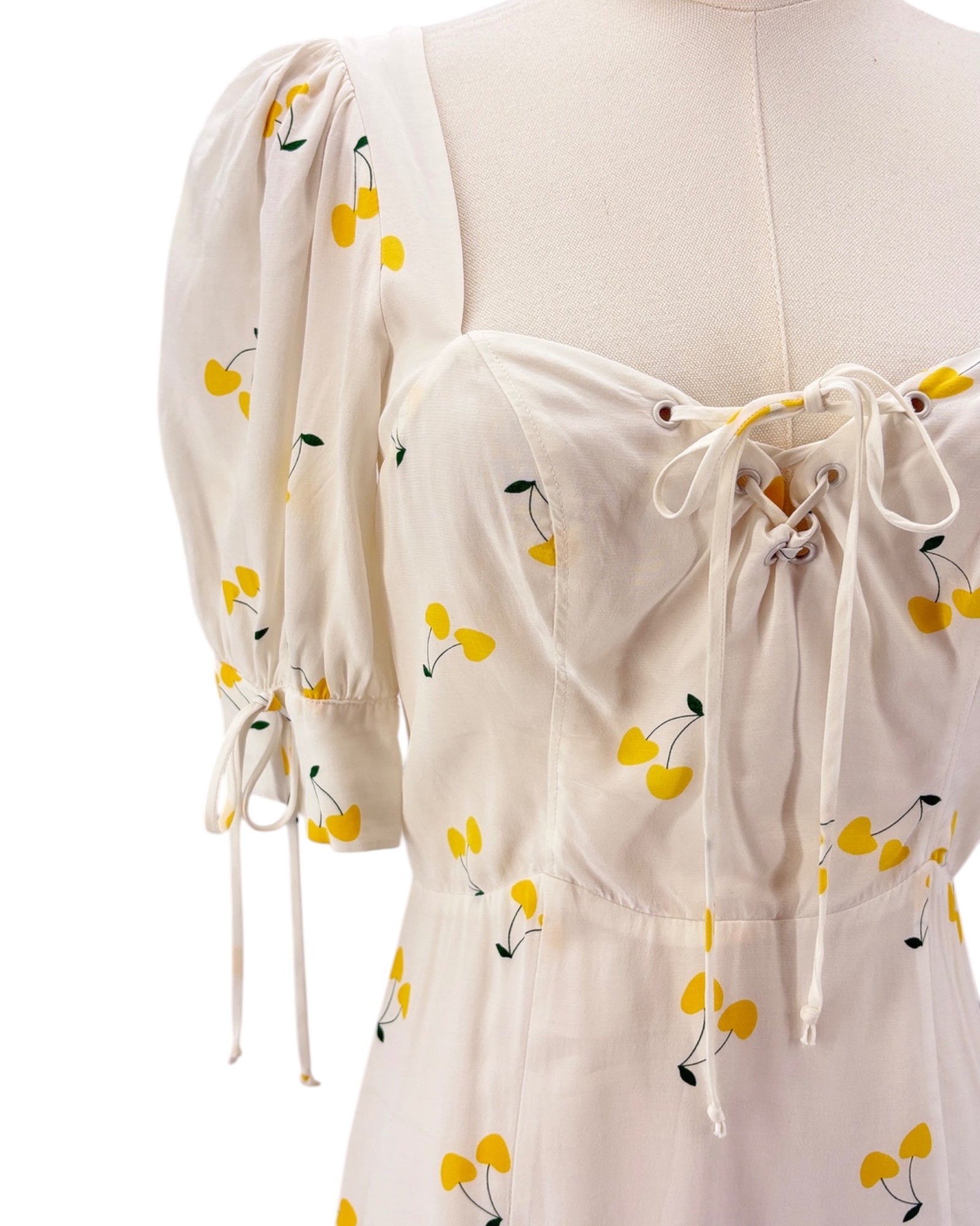 For love and lemons white dress with yellow floral pattern on a mannequin against a white background