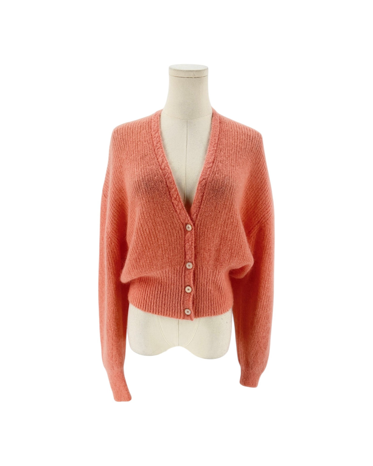A coral pink knit cardigan sweater displayed on a cream-colored mannequin torso against a plain white background.