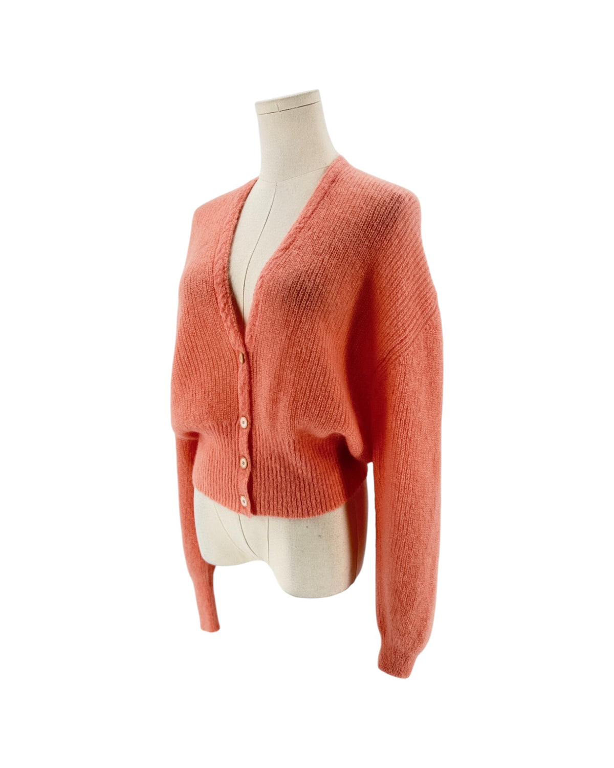 A coral pink knit cardigan sweater displayed on a cream-colored mannequin torso against a plain white background.