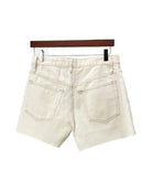 Beige denim shorts on a hanger against a white background
