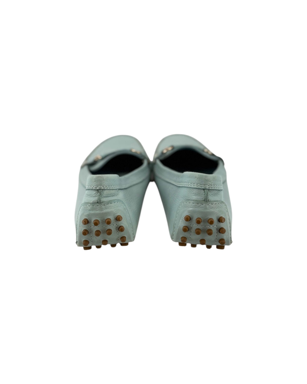 A pair of light Blue green leather mule shoes with brown rubber spikes on the soles, shown from the back against a plain white background.