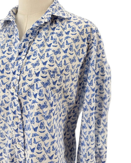 A long-sleeve button-up shirt with an all-over blue and white butterfly pattern, displayed on a cream-colored mannequin torso against a plain white background.