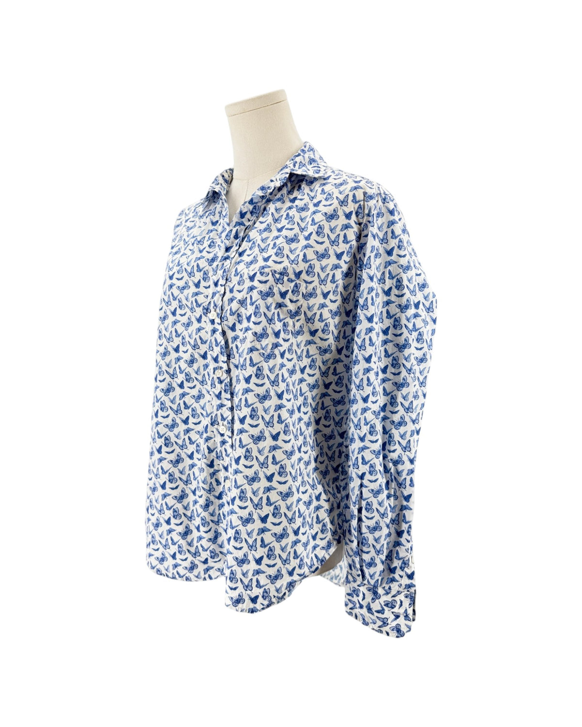 A long-sleeve button-up shirt with an all-over blue and white butterfly pattern, displayed on a cream-colored mannequin torso against a plain white background.