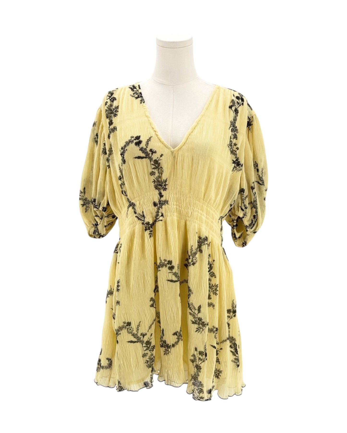 Yellow dress with black floral pattern on a mannequin against a white background