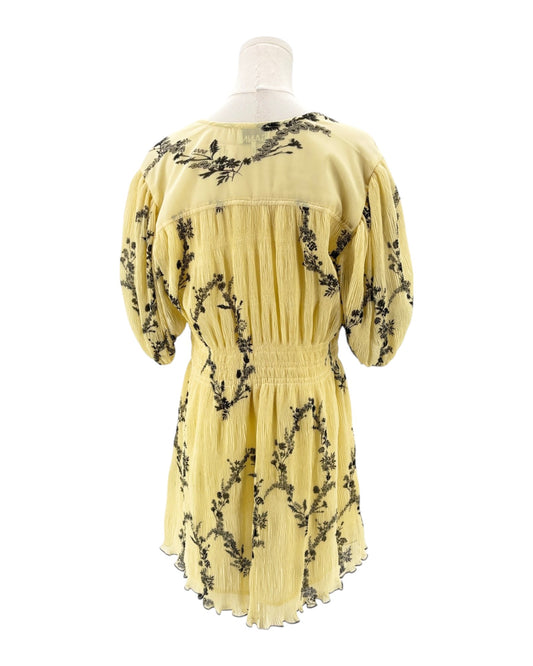 Yellow dress with black floral patterns on a mannequin against a white background