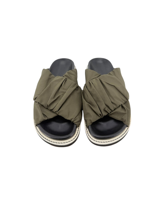 Black slip on sandals with two thick green straps across the top on a white background
