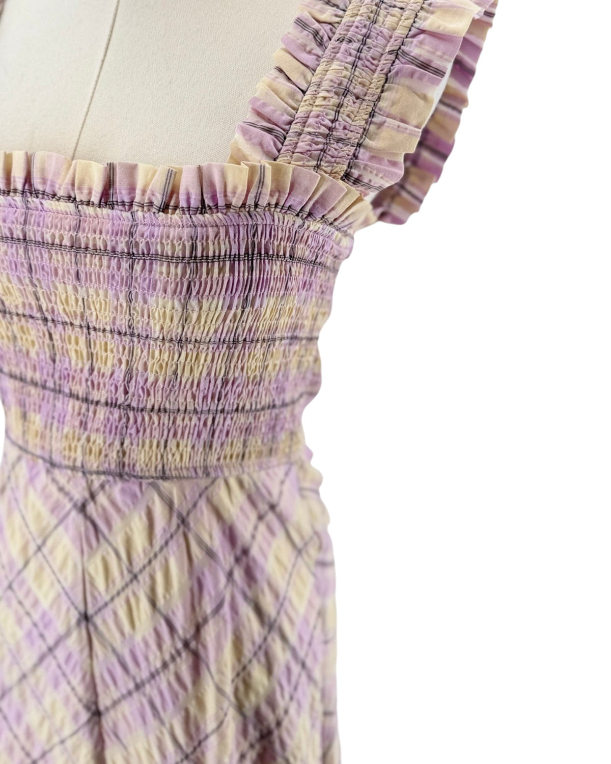 A sleeveless, smocked maxi dress with a purple and beige plaid pattern, displayed on a mannequin against a white background.