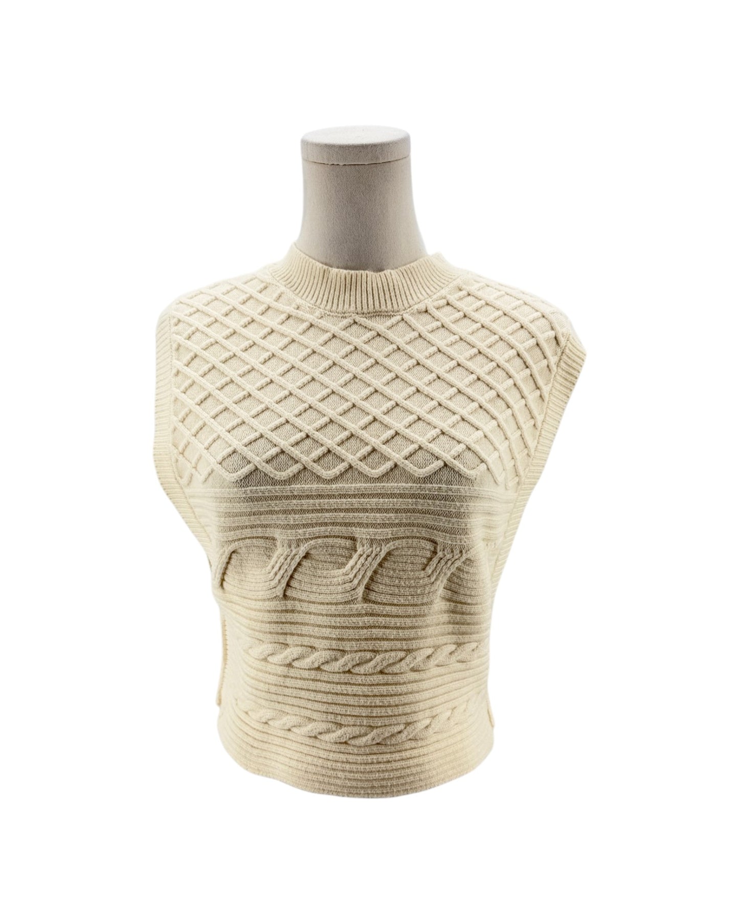 A cream-colored sleeveless cable-knit sweater displayed on a mannequin torso against a plain white background.
