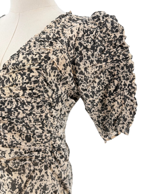 A close-up of a beige and black leopard-print dress displayed on a cream mannequin torso, showing a ruffled short puff sleeve and gathered fabric detail against a white background.