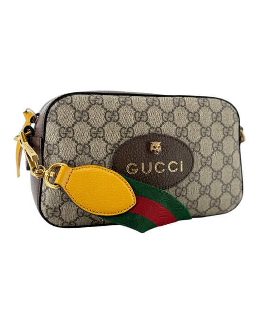 Small leather double G gucci handbag with a yellow zipper tassel, red and green strap, and with small all over double g print on a white background