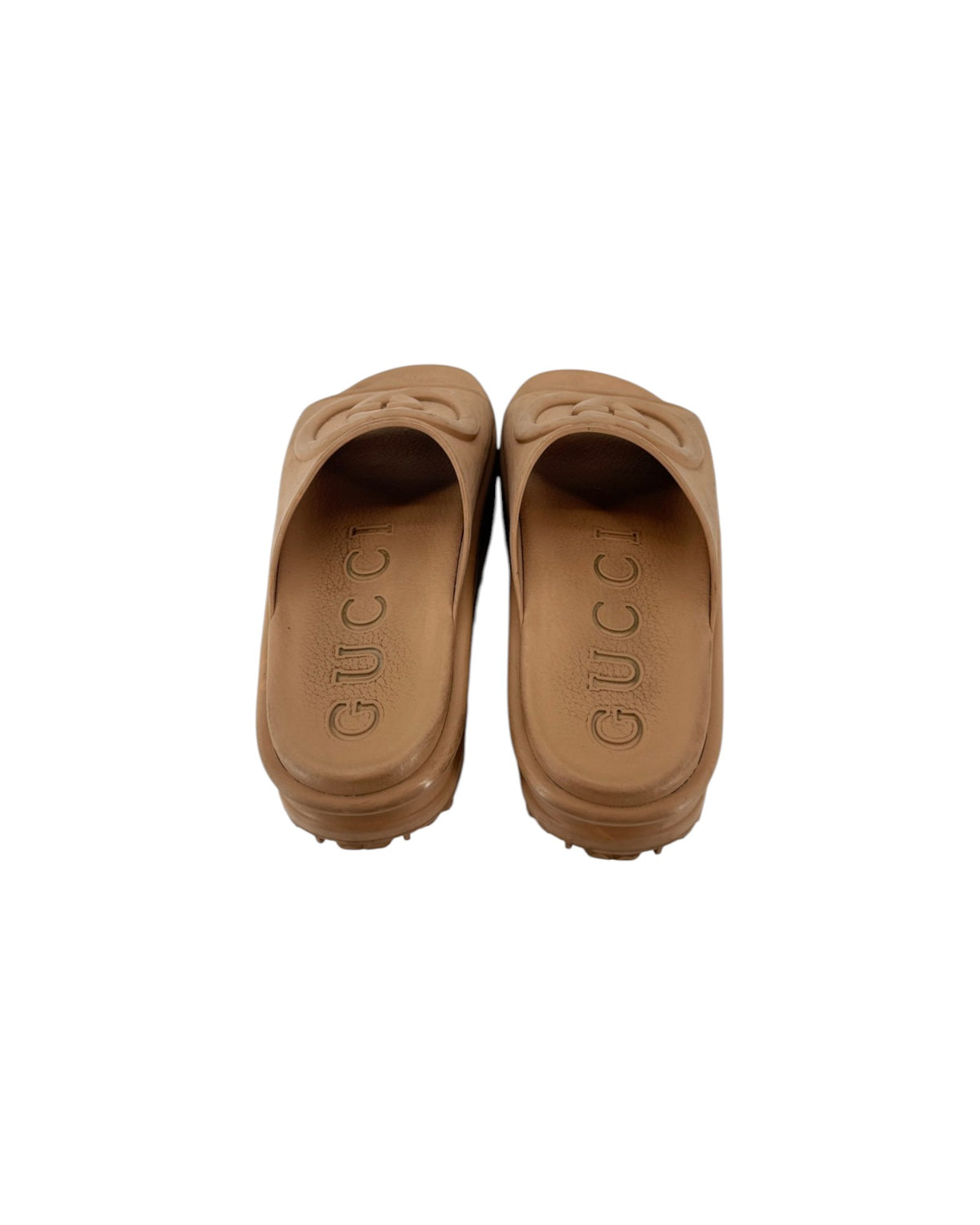 A pair of tan leather slide sandals with the brand name 'GUCCI' embossed on the sole, shown from a top-down view on a white background.
