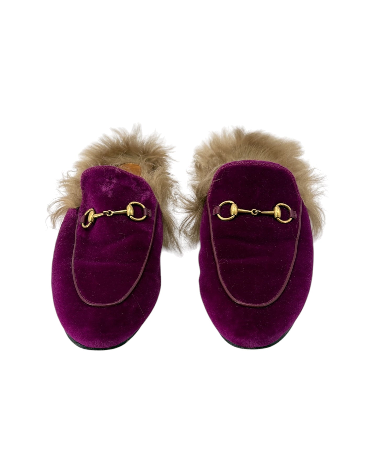 Pair of purple velvet slippers with fur trim and gold hardware on a white background