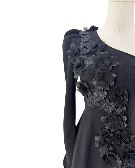 Up close photo of a black floral applique on a one sleeve mini dress