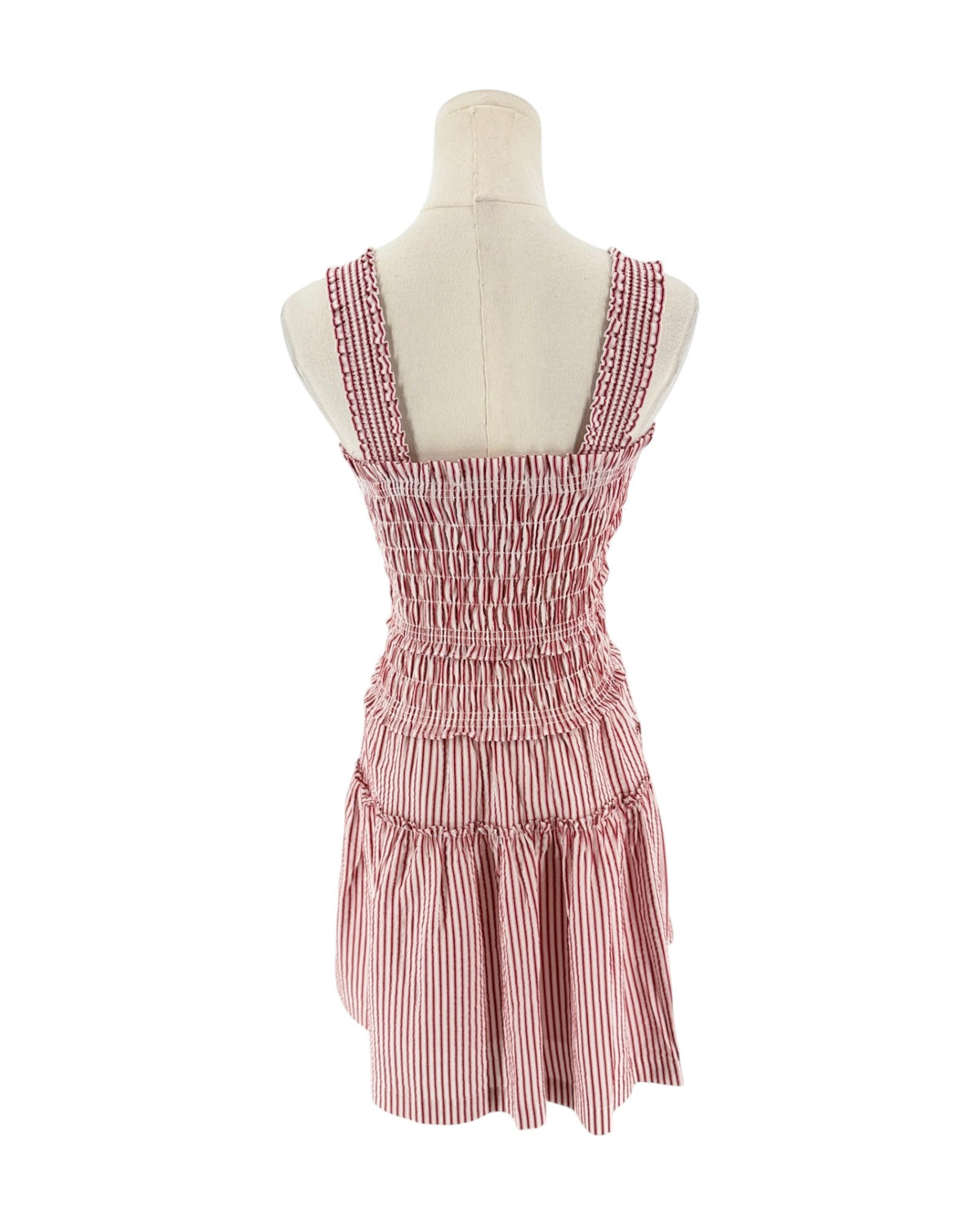 A sleeveless smocked dress with tie shoulder straps, featuring a striped red and white print on a white background, displayed on a mannequin torso against a white background.