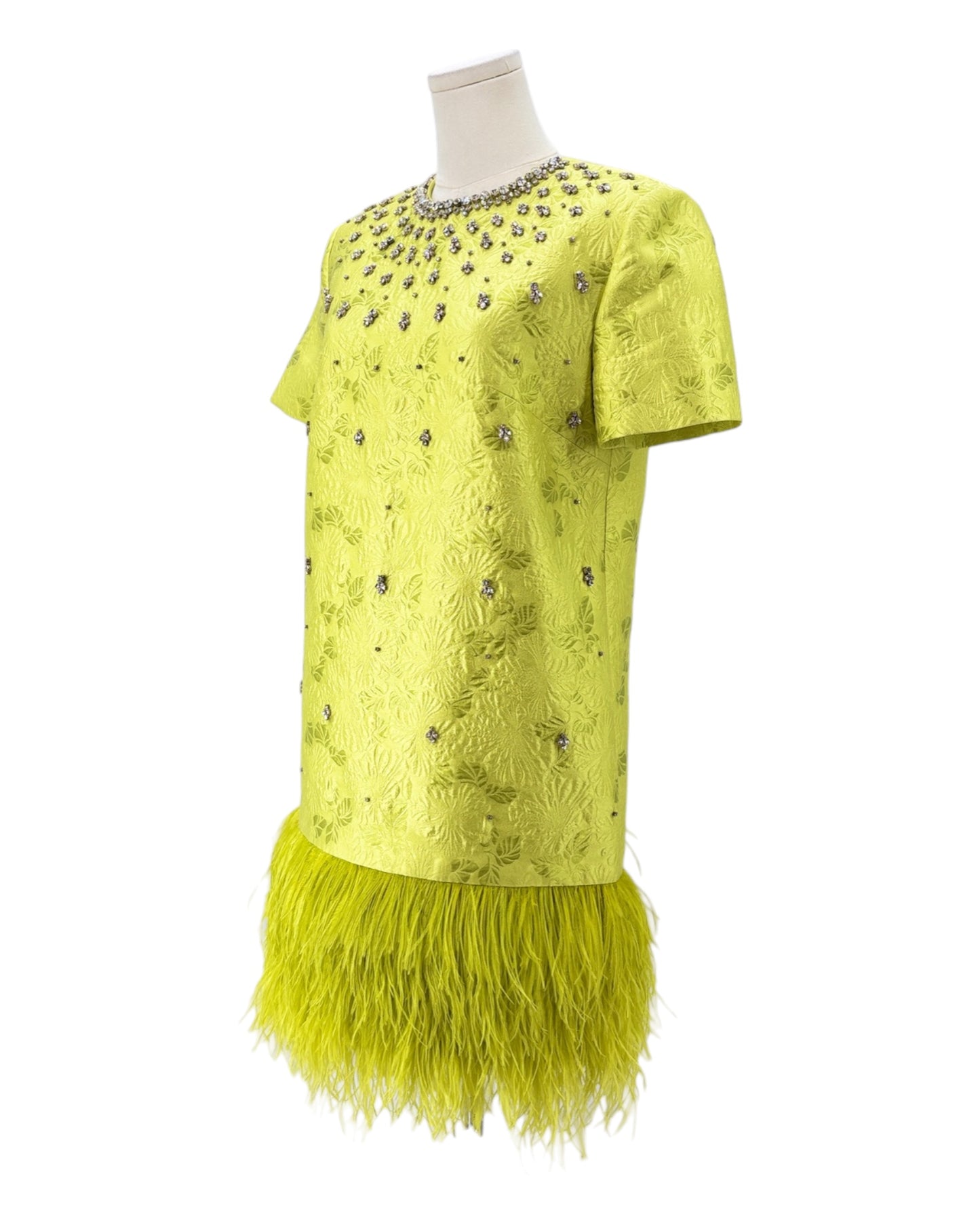 Green dress with feathered skirt on a mannequin against a white background