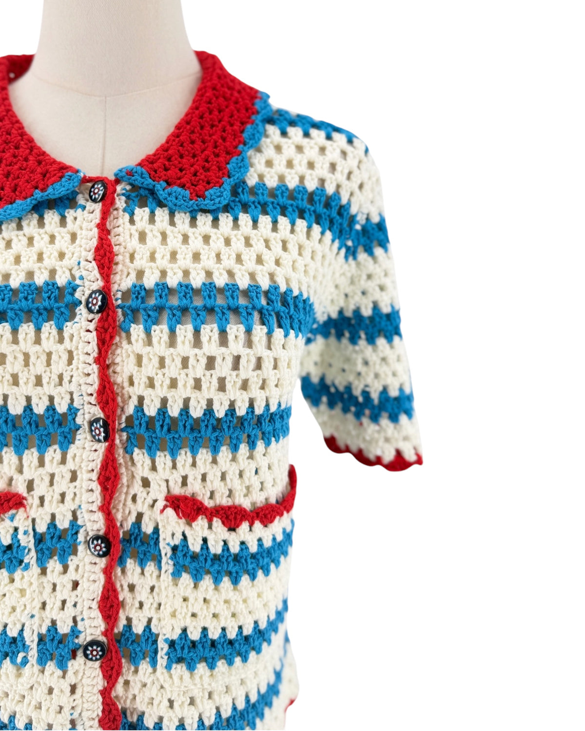 Blue white and red short sleeve, front patch pockets, button front, vertical striped print, peter pan style collar cardigan sweater on a white background on a mannequin