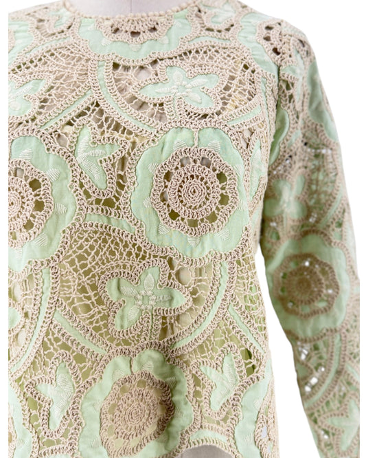 Long sleeve, minty pastel green and off white cream, tactile open-work lace, scalloped edge. On a white background on a mannequin.