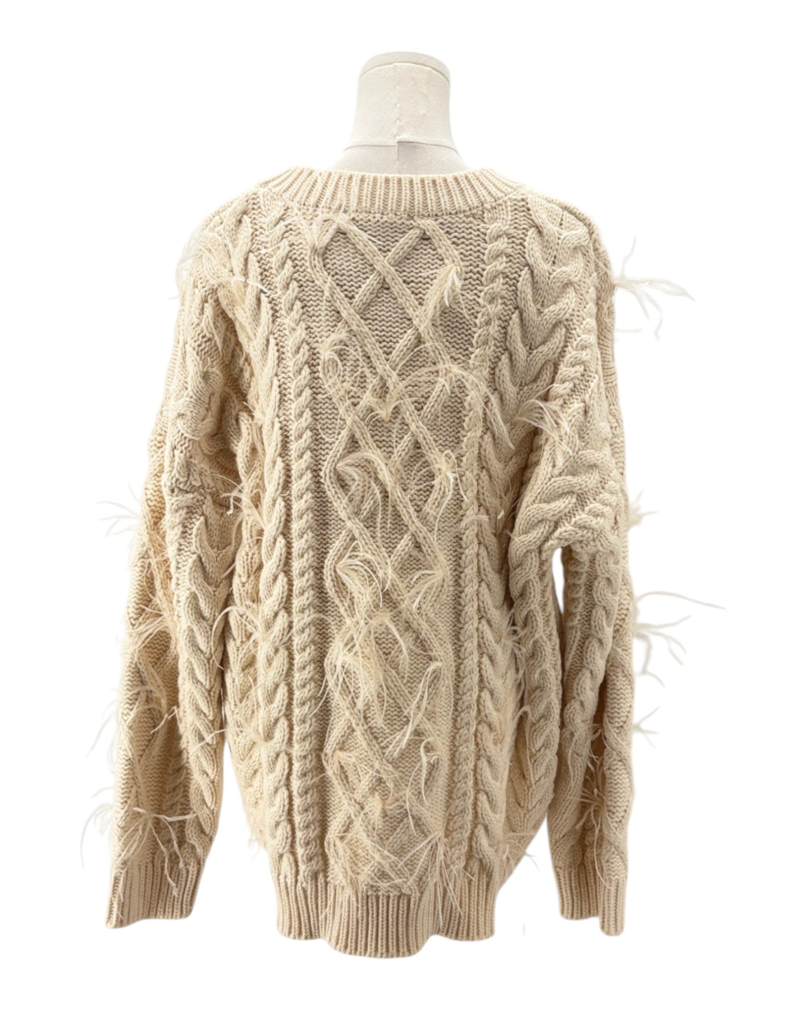 Beige cable knit sweater on a mannequin against a white background