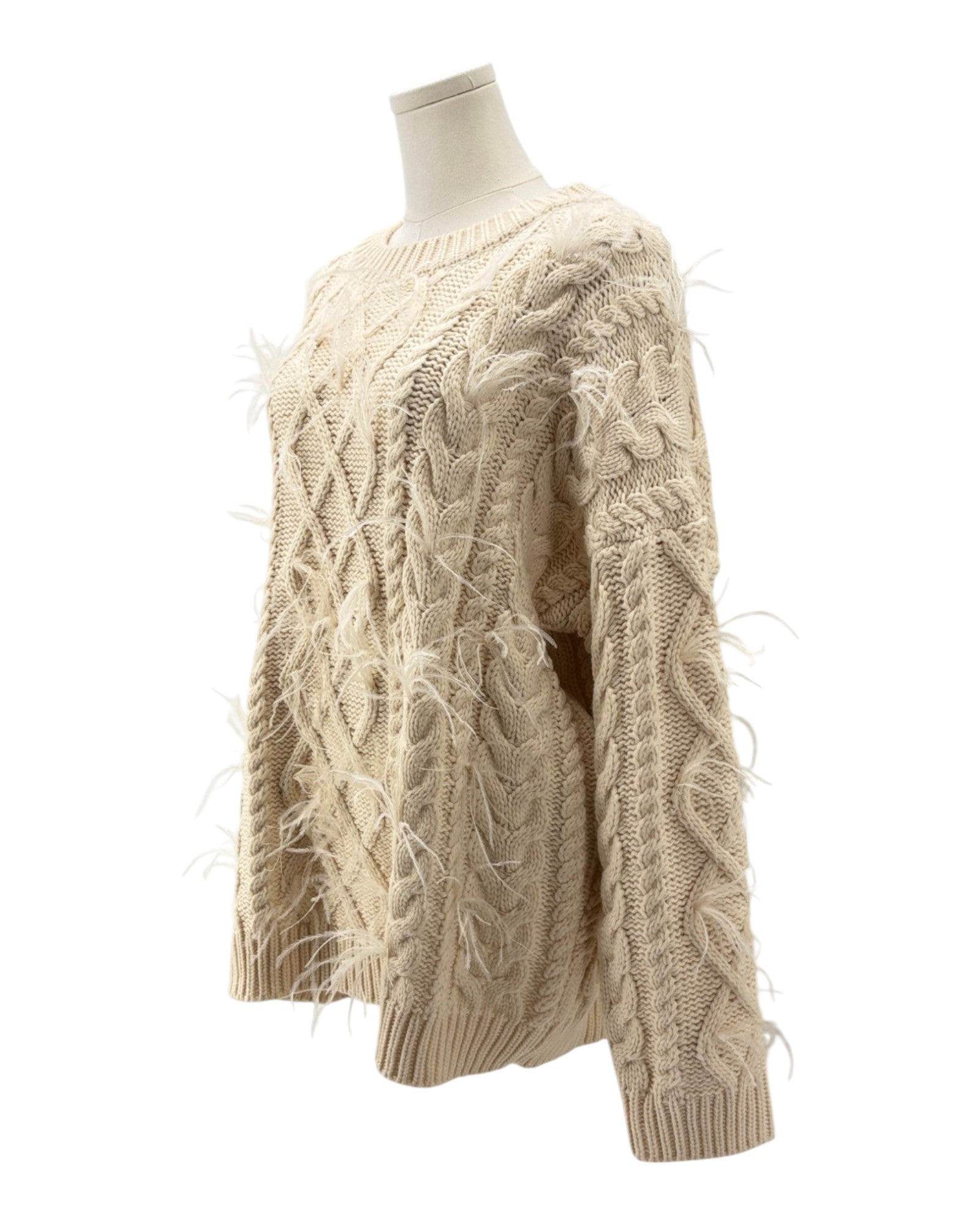 Beige cable knit sweater on a mannequin against a white background