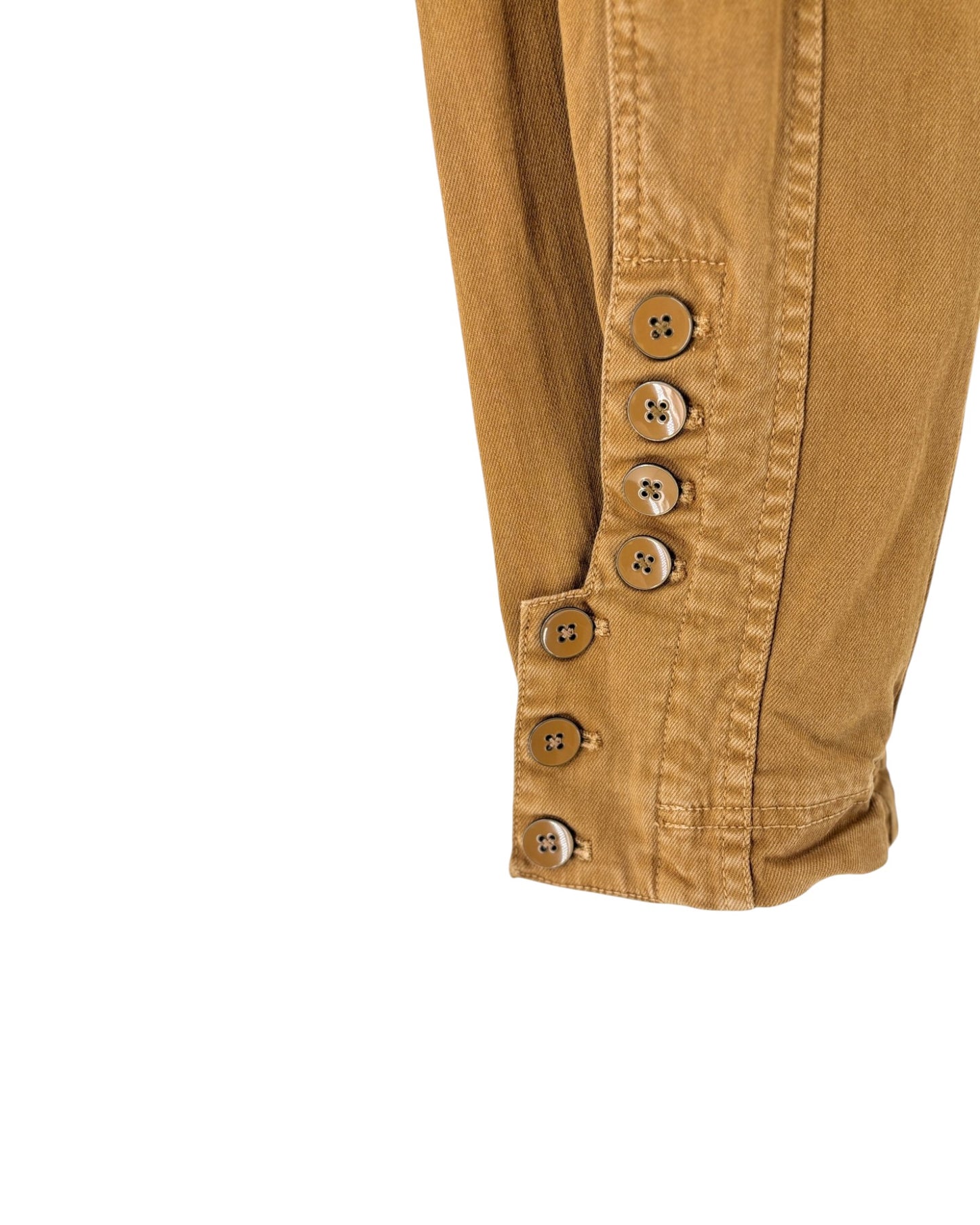 Close-up of a tan or camel-colored fabric garment, showing a buttoned cuff detail with five decorative buttons on a plain white background.