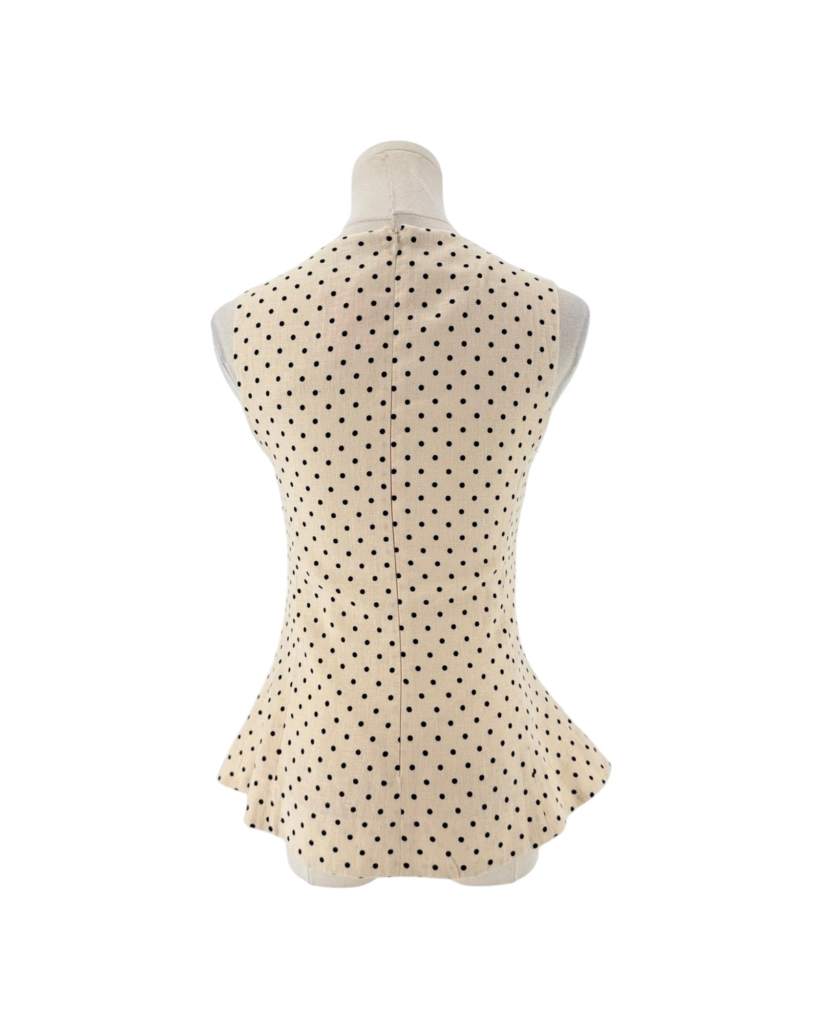 Sleeveless cream peplum top with back polka dots and a zipper down the back on a mannequin on a white background