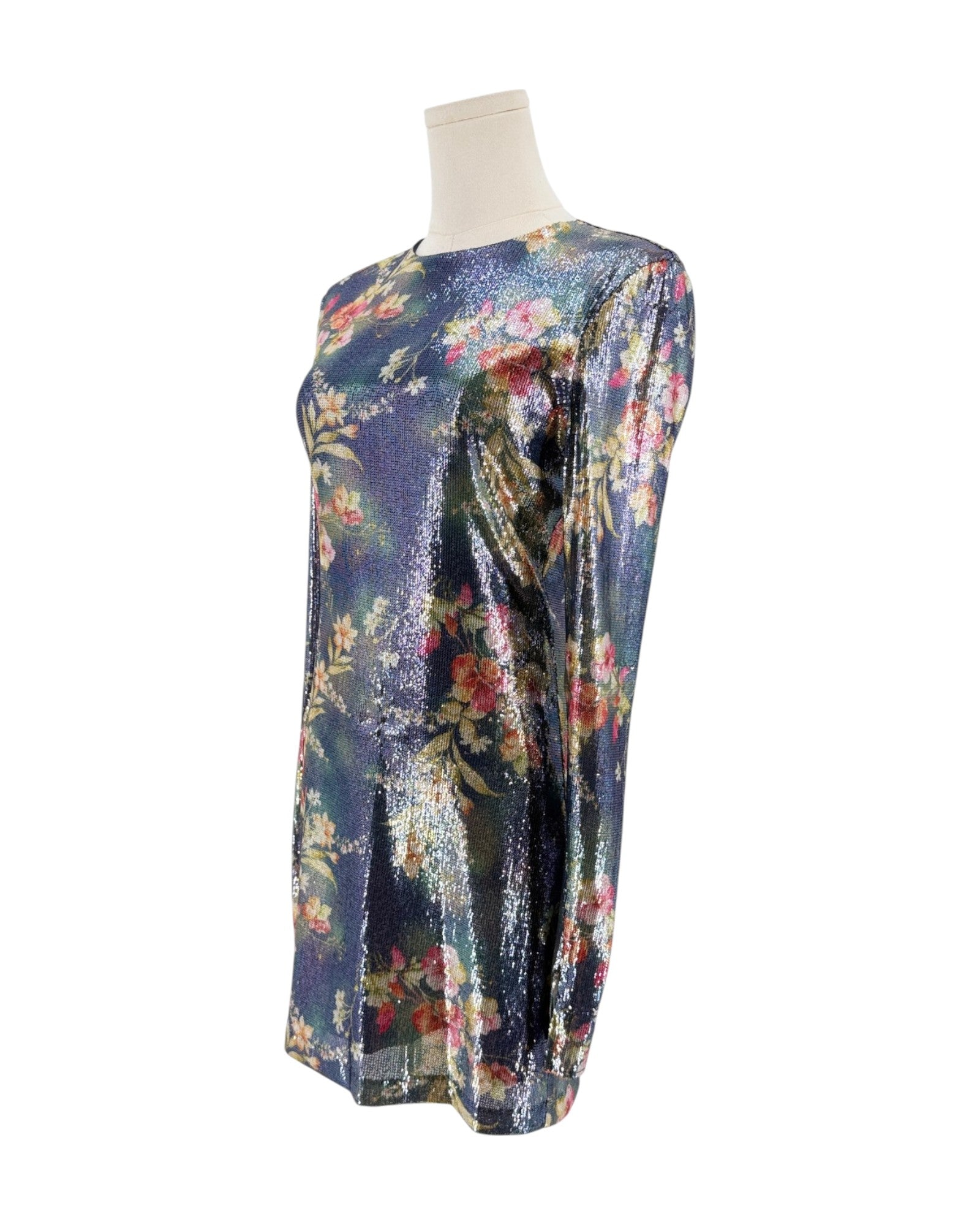 A long-sleeve tunic dress with a shimmering floral print on a dark blue-purple base, displayed on a cream mannequin torso against a plain white background.