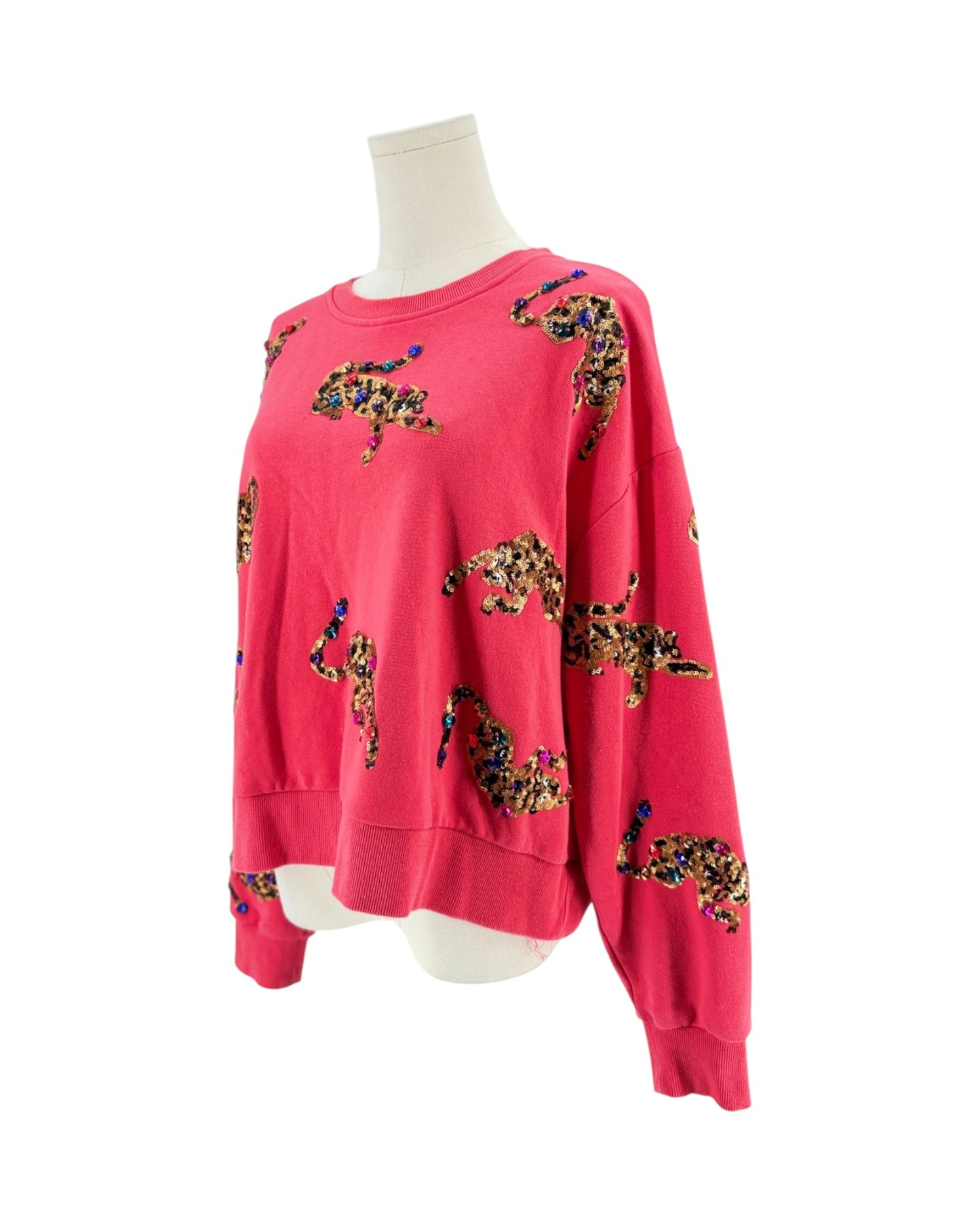 A bright pink crewneck sweatshirt with a leopard print pattern, displayed on a white mannequin torso against a plain white background.