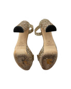Pair of gold glitter high-heeled shoes on a white background