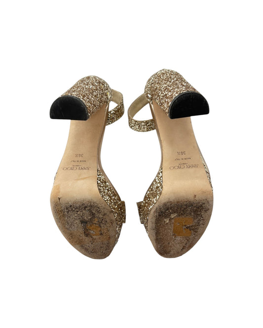 Pair of gold glitter high-heeled shoes on a white background