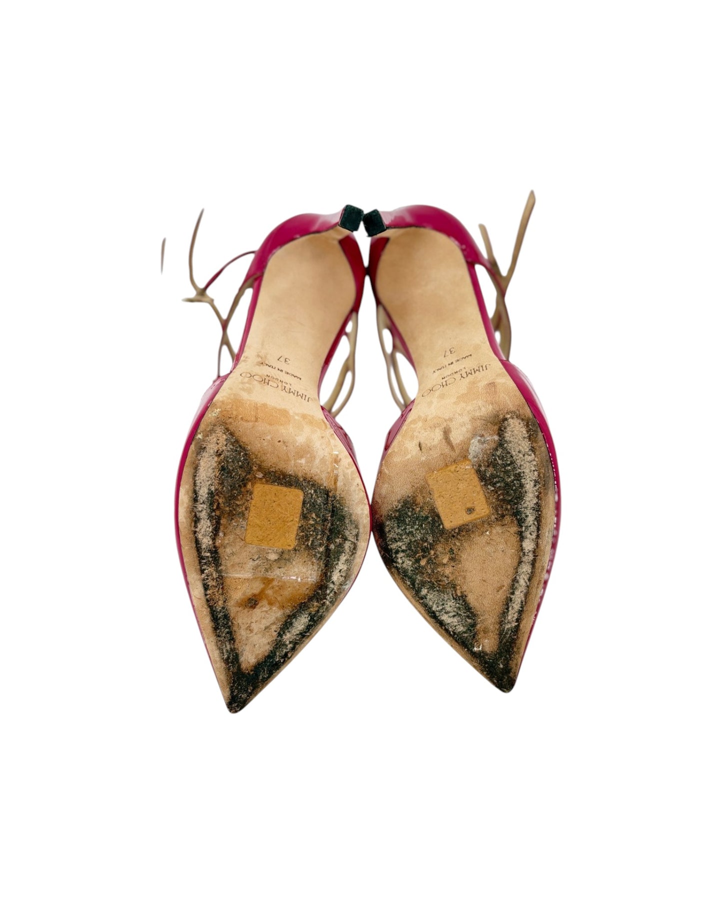 A pair of pointed-toe slingback heels shown from the sole, featuring a bright pink upper and a heavily worn, patched beige and black rubber sole.