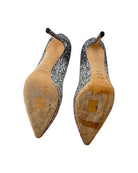 Pair of glittery high-heeled shoes with worn soles on a white background