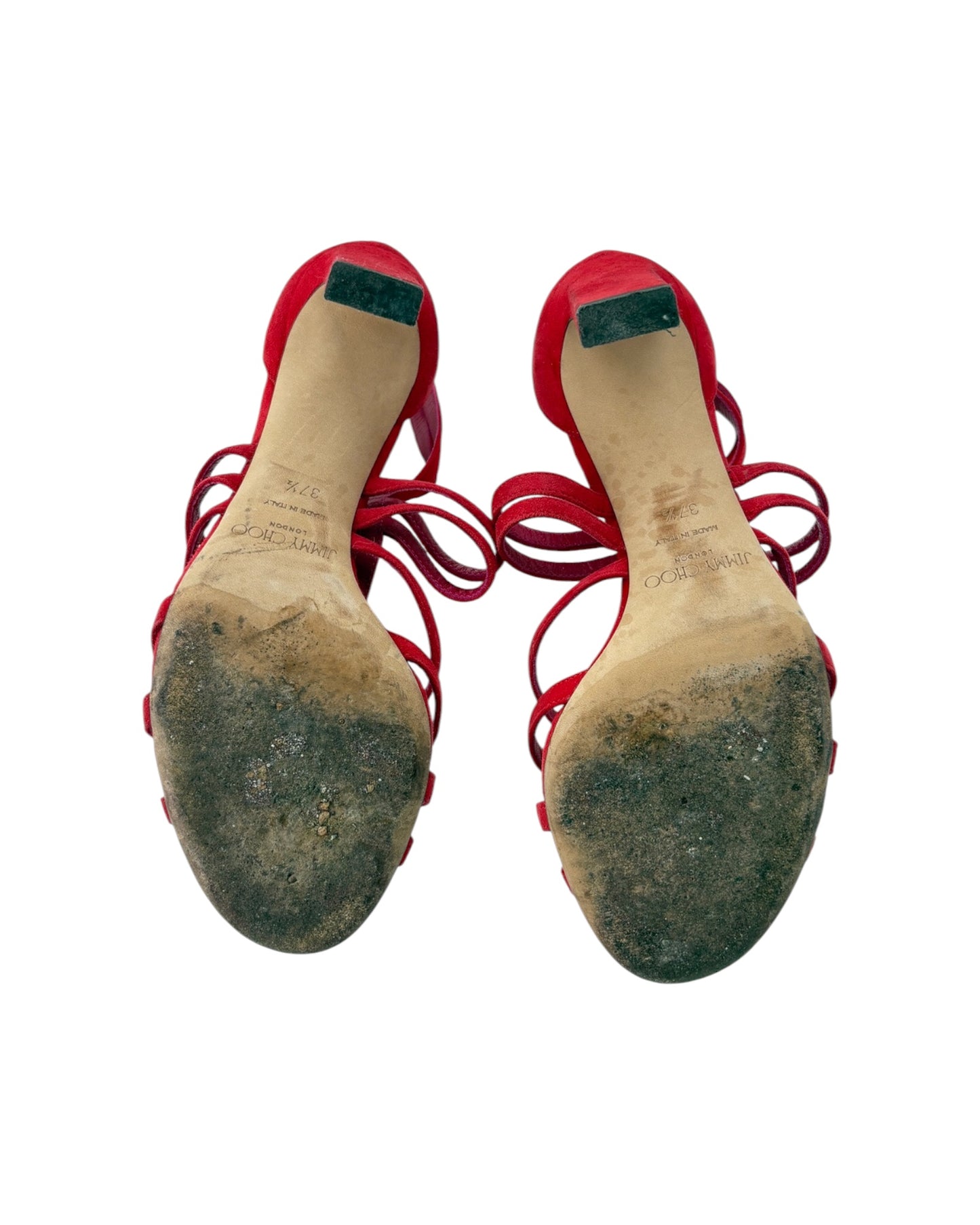 Pair of red high-heeled shoes with worn soles on a white background