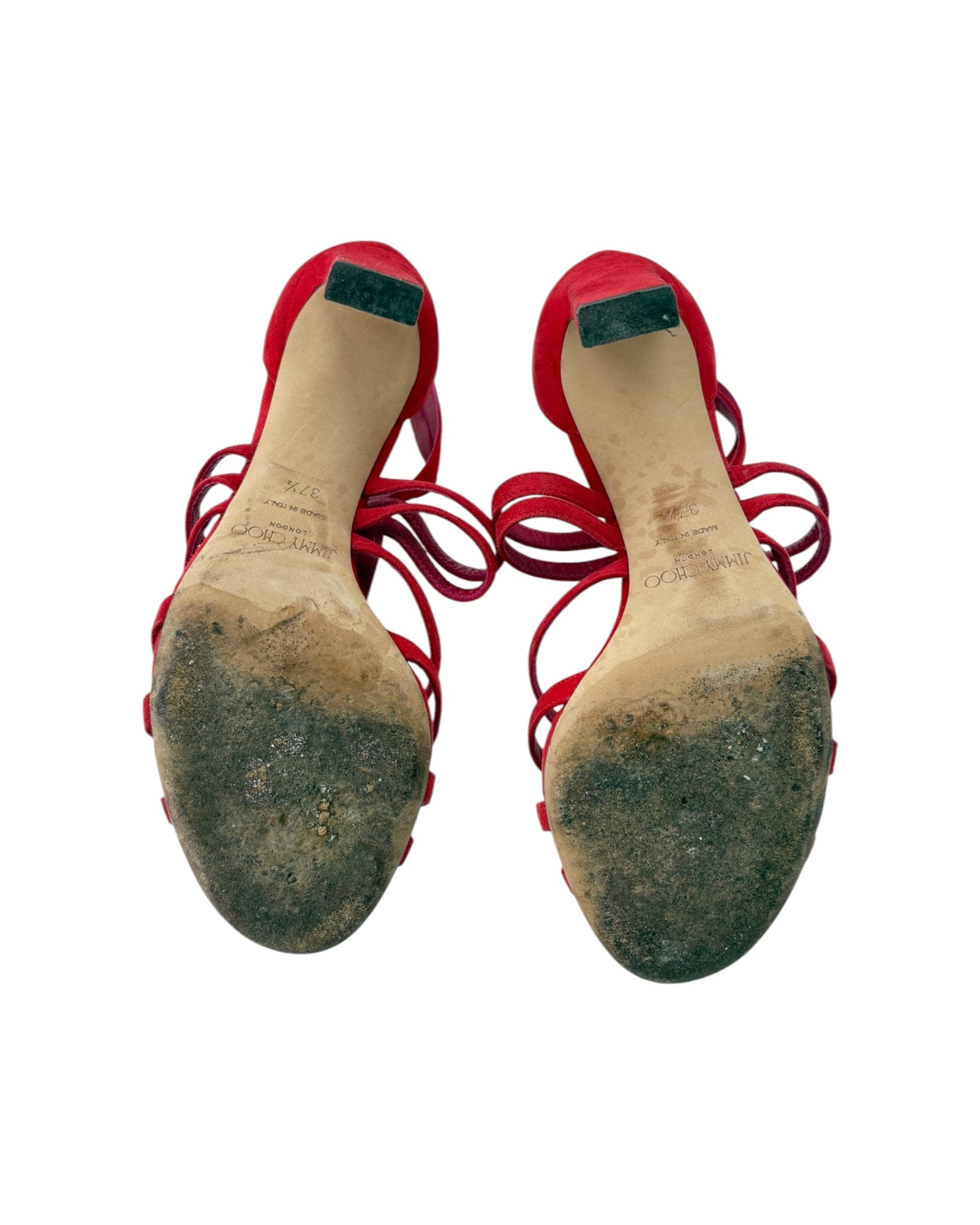 Pair of red high-heeled shoes with worn soles on a white background