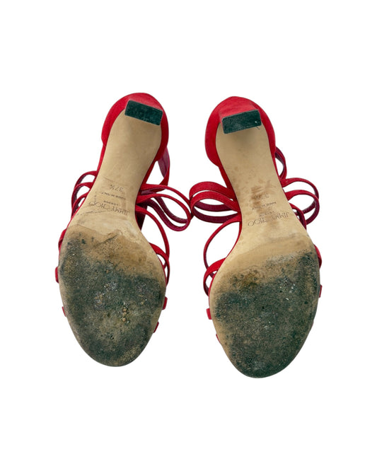Pair of red high-heeled shoes with worn soles on a white background