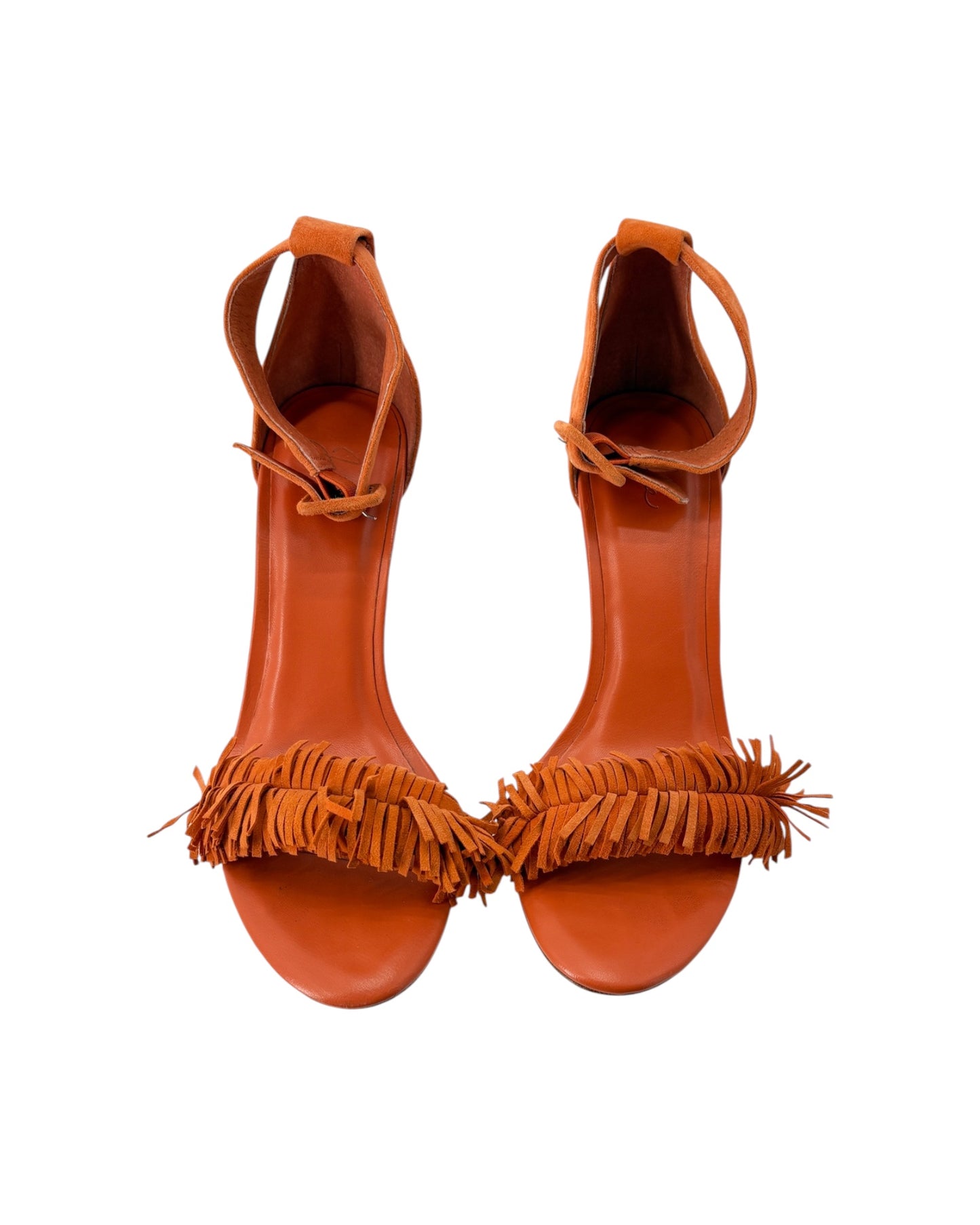 Pair of orange high-heeled sandals with fringe details on a white background