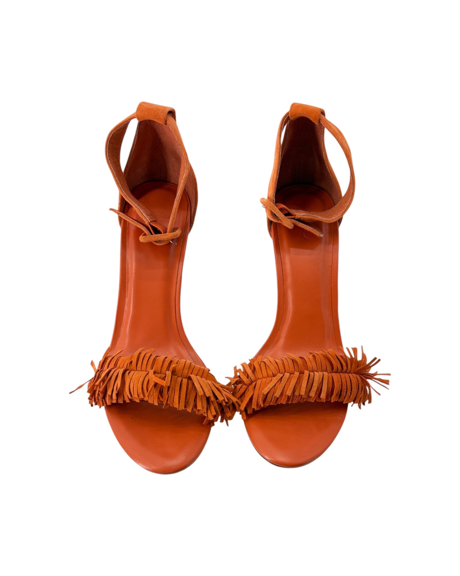Pair of orange high-heeled sandals with fringe details on a white background