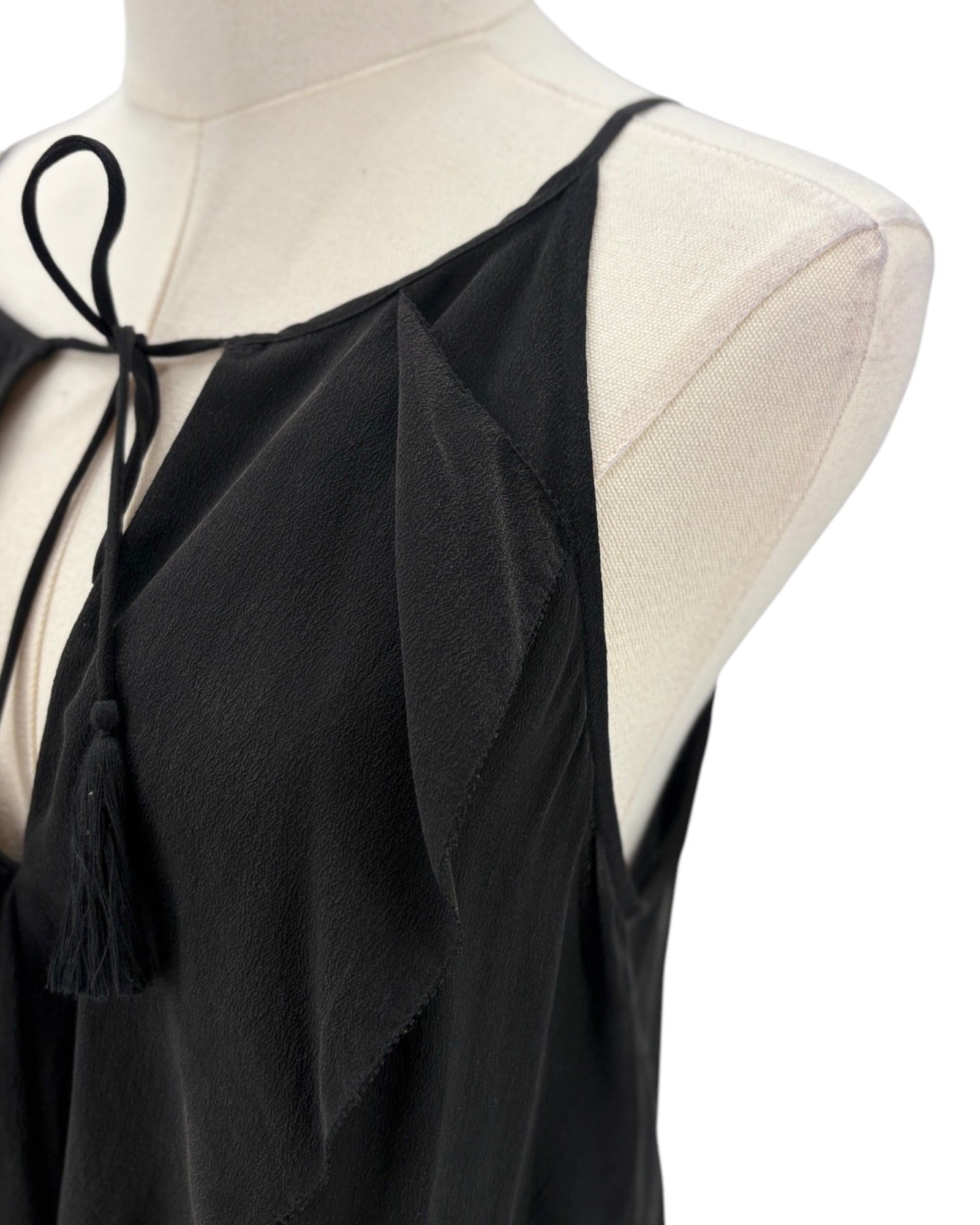 Black sleeveless top with tie details on a mannequin against a white background