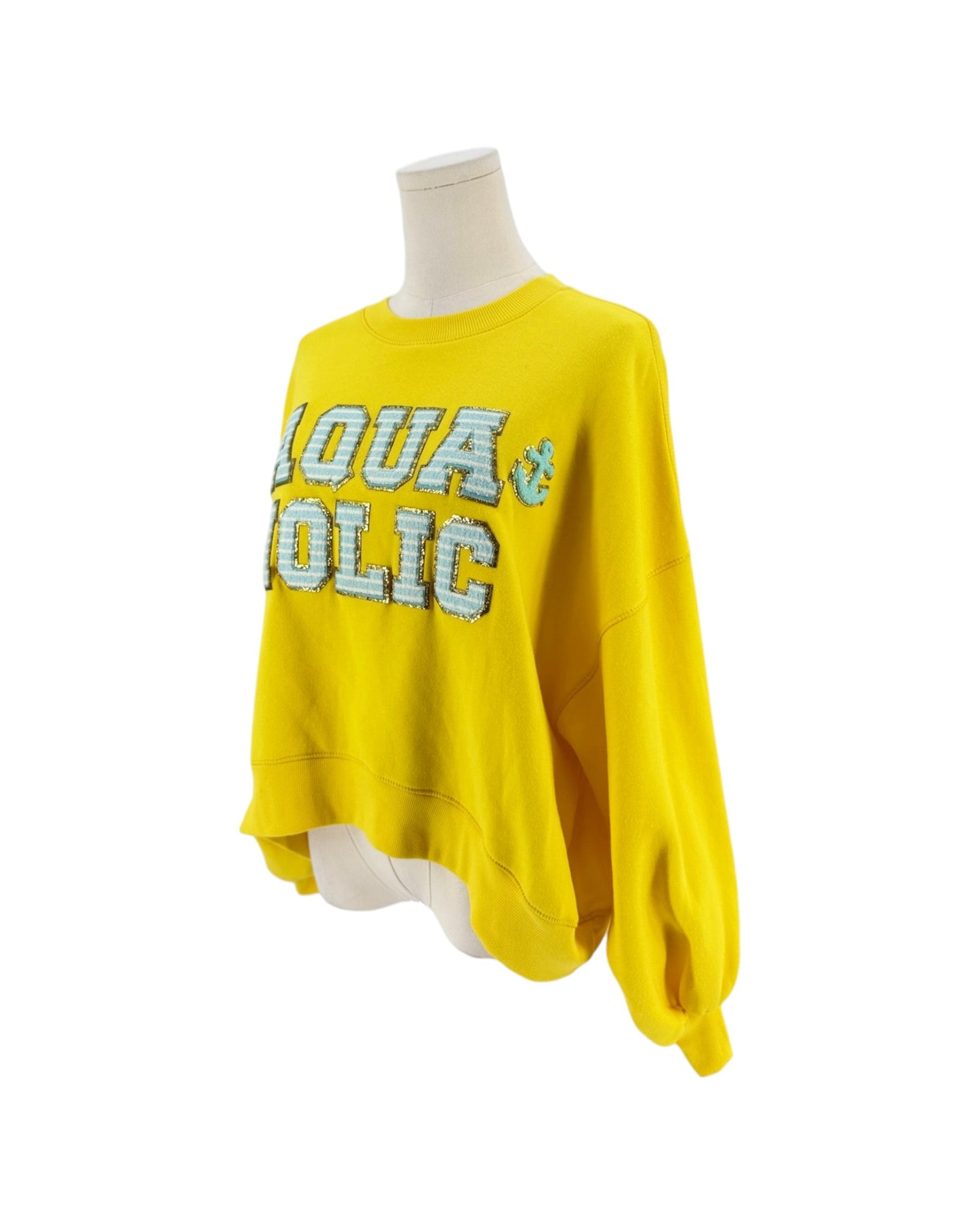 A bright yellow long-sleeve sweatshirt displayed on a mannequin torso against a plain white background. The front features the words 'AQUA POLIC' in large outlined letters with a light blue and white patterned fill, alongside a small anchor graphic.