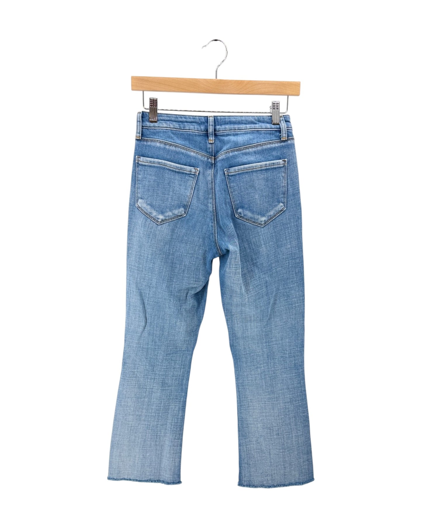 Light blue denim jeans shown from the back, hanging from a wooden hanger against a plain white background.