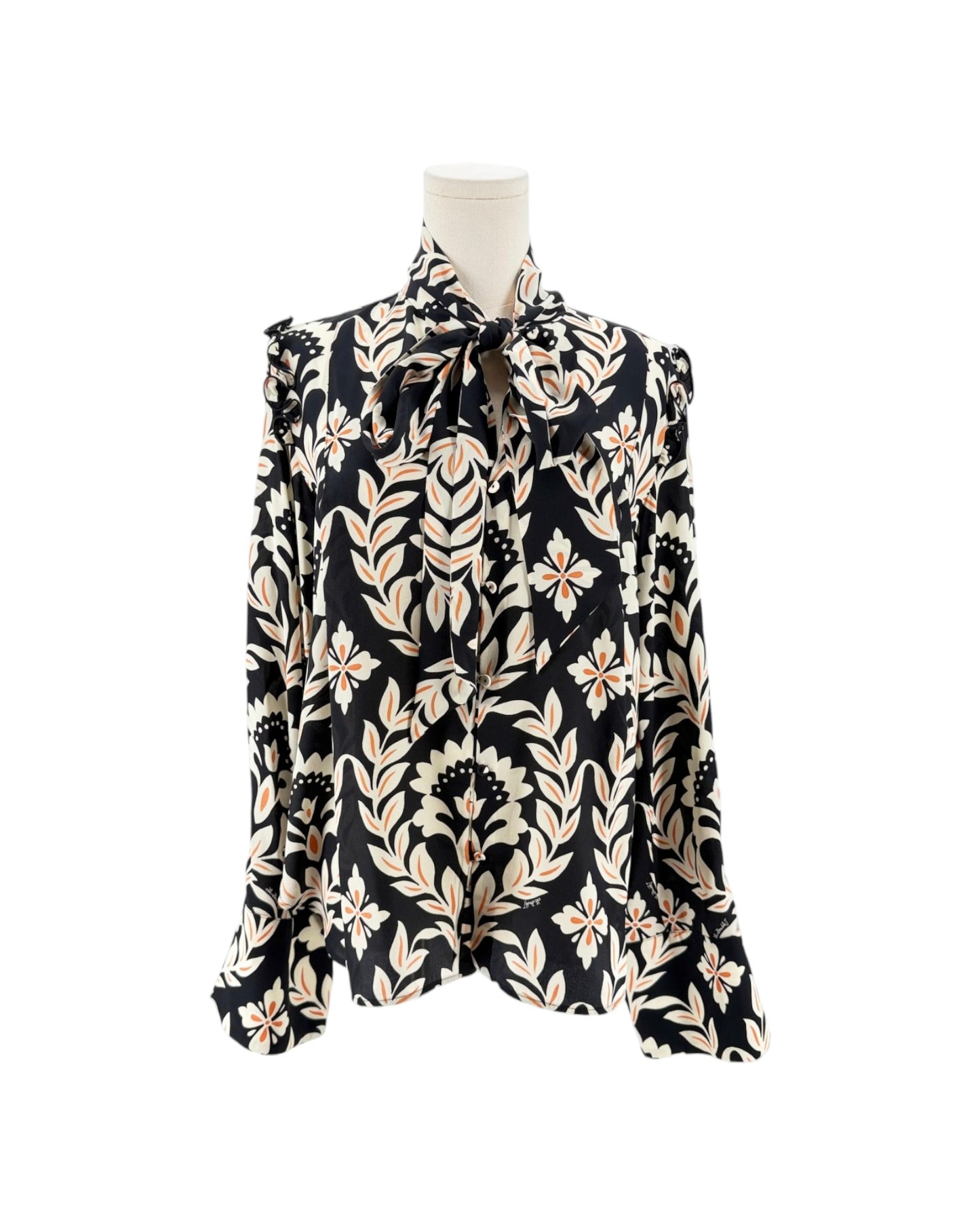 A long-sleeve blouse with a black background and a beige botanical leaf pattern, displayed on a mannequin torso against a white background.