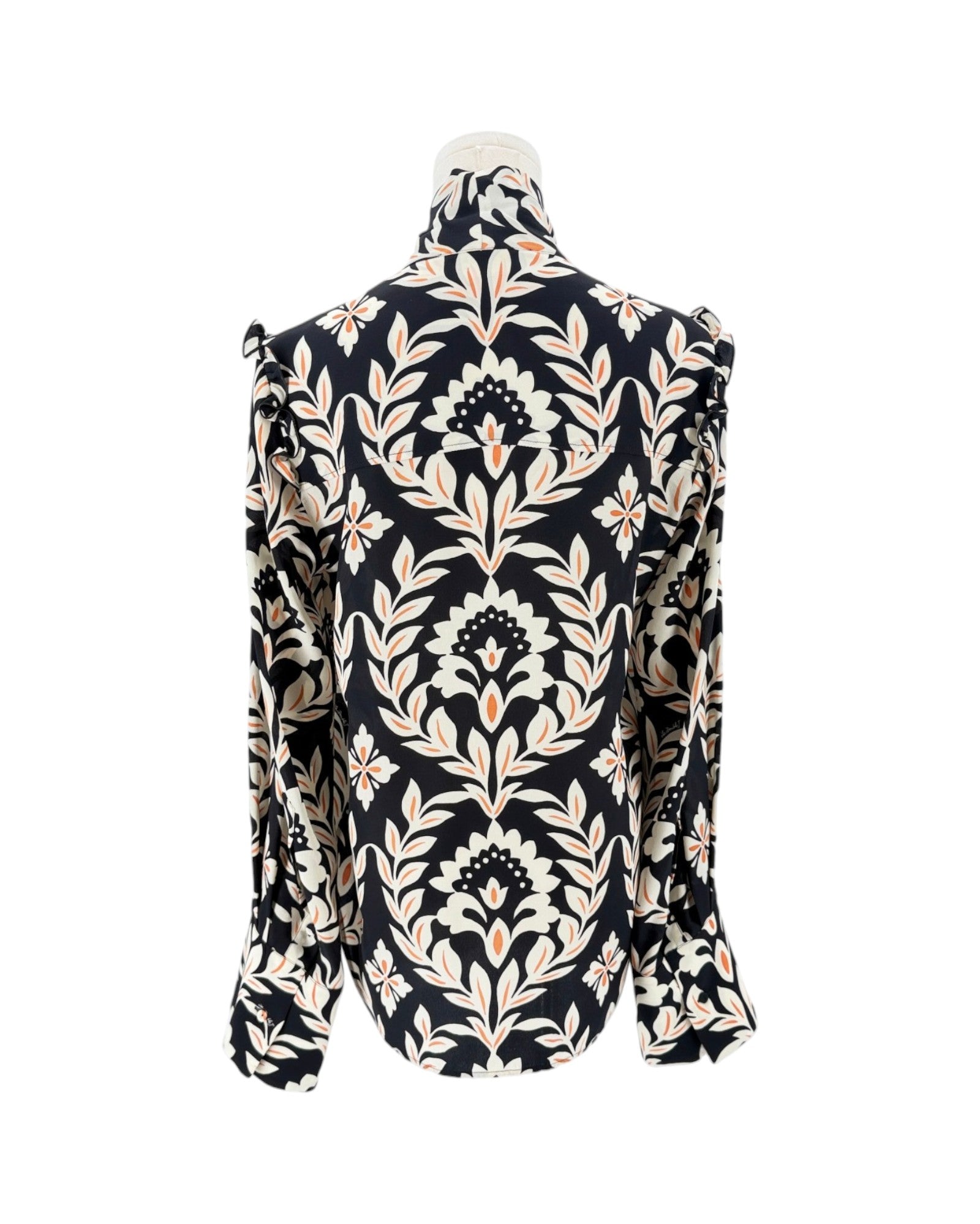 A long-sleeve high-neck blouse with a dramatic ruffled collar and shoulders, featuring an intricate black, beige, and white damask floral pattern, displayed on a mannequin against a white background.