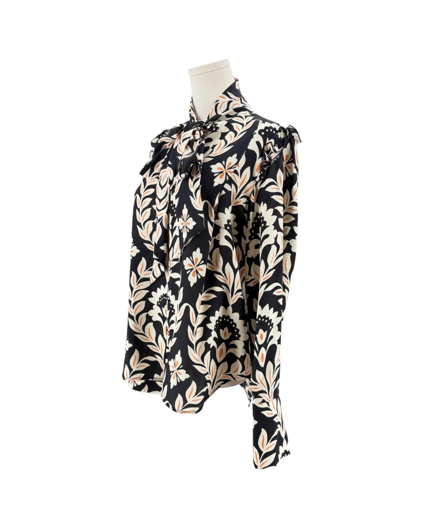 A long-sleeve blouse with a black background and a beige floral pattern, displayed on a mannequin torso against a white background.