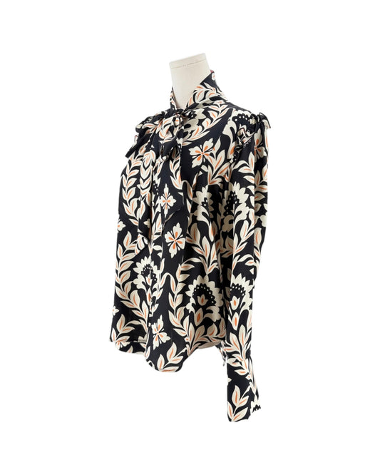 A long-sleeve blouse with a black background and a beige floral pattern, displayed on a mannequin torso against a white background.