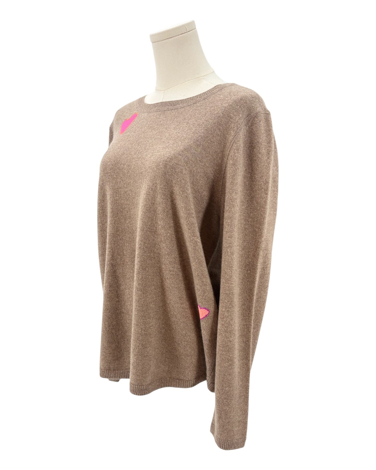 Tan sweater with colorful heart patterns on a mannequin against a white background