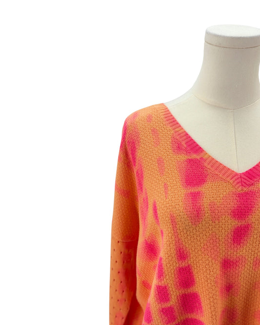 Orange and pink patterned sweater on a mannequin against a white background